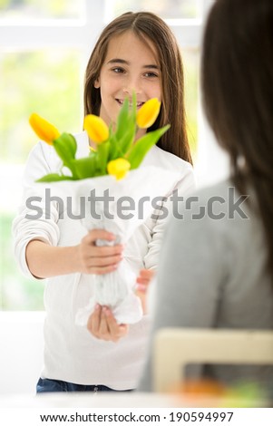 Cute girl giving flowers her mom for mother\'s Day