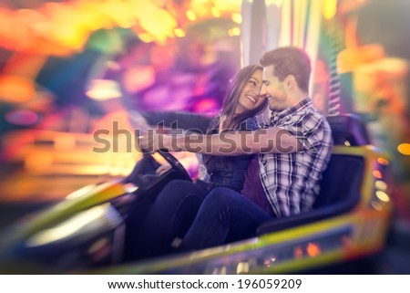 Happy couple ride bumper car on a fun fair amusement