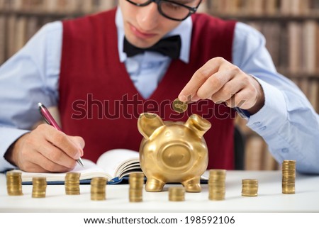 young accountant male counting money and putting in piggy bank