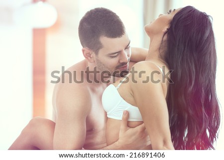 Sexy young couple kissing and playing in bed.
