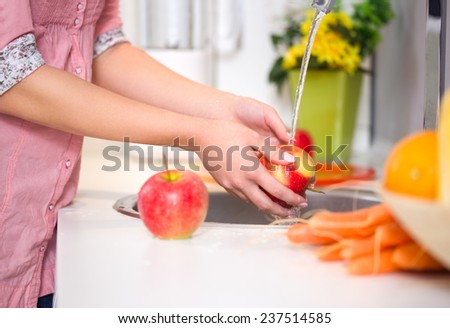 Washing fruit, woman washing red apple under the tap