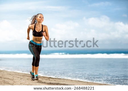 Jogging athlete woman running at sunny beach. Fitness runner girl training outside by the ocean sea in full body length in summer