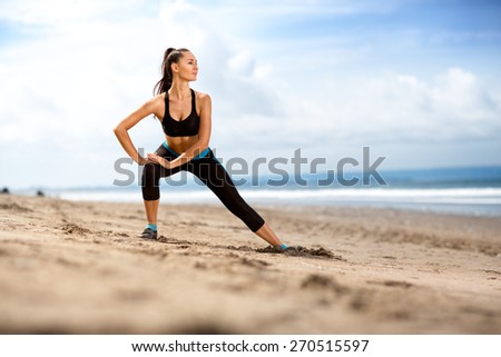 Fit woman  doing exercises for legs on the beach on a sunny day