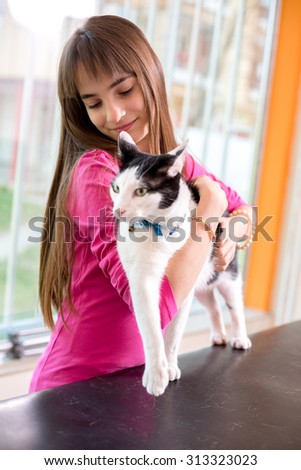 Girl with her restless sick cat trying to calm her down at vet clinic