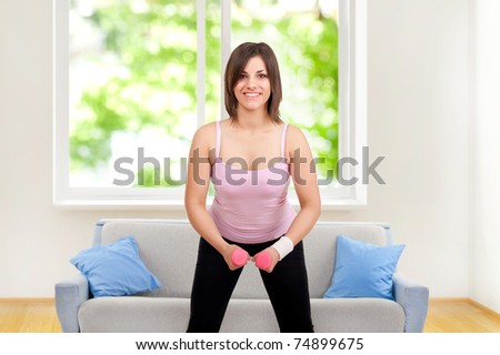smiling happy woman exercising with dumbbells at home