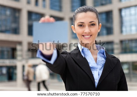 blank business card,  businesswoman with blank business card in a hand, office building as background