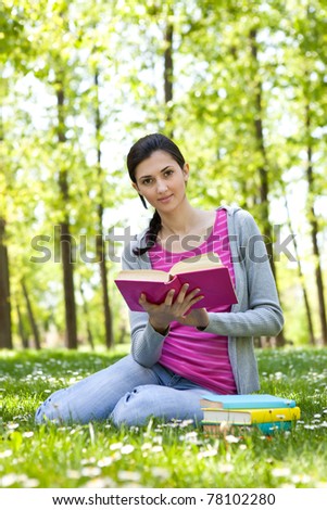 cute girl reading a book on the grass outside