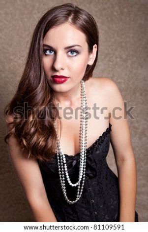 young   model in black dress and pearls, looking at camera
