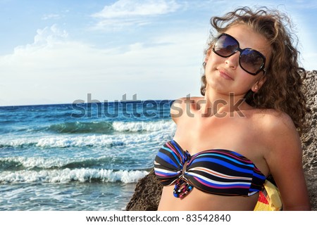 attractive young woman sunning on rock , relaxing on beach