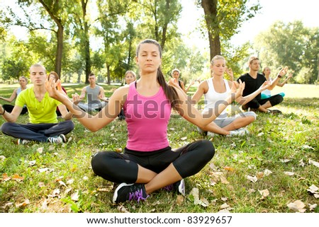 group of people relaxing with meditation in park