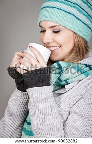 Pretty winter teenage girl holding mug with hot beverage
