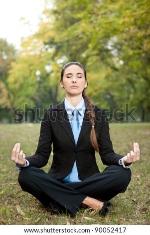 relaxed,  young businesswomen sitting in yoga position on grass