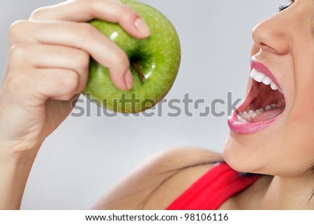 beautiful young woman biting a fresh green apple