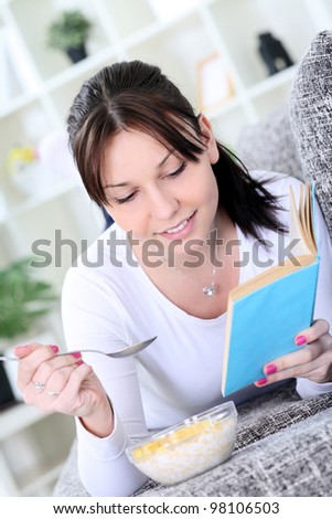 Young woman in living room resting and eating snack