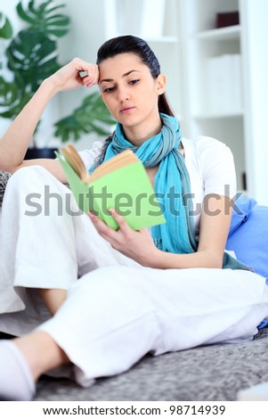 Young woman reading  a boring book, tired student at home