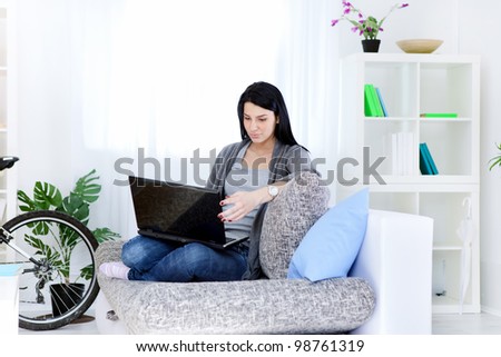 smiling woman in living room sitting on sofa using laptop