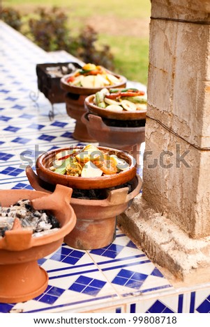 tajine ceramic cookware slow cooking over wood charcoal at outdoor restaurant morocco Africa