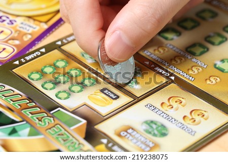 Coquitlam BC Canada - June 15, 2014 : Woman scratching lottery ticket called Monopoly. It\'s published by BC Lottery Corporation has provided government sanctioned lottery games.