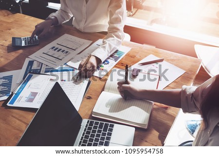 business consulting or finance budget plan, business advisor holding pen pointing to explain method profit with business owner use pen write to notebook and use laptop computer. 商業照片 © 