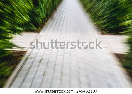 Image of bricks pathway and green trees in the park, motion blur effect