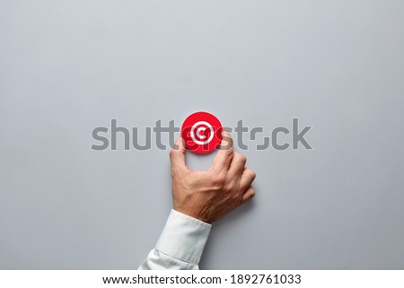 Businessman hand holding a red badge with copyright symbol. Property rights and brand patent protection in business concept.