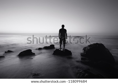 black and white seascape with alone man on the rocks