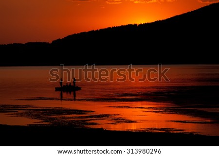 Red sunset and fishing boat silhouette, high mountain bulgarian Batak dam lake