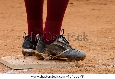 Close up of dirty baseball cleats standing on base with dark red socks