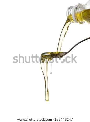 Pouring oil on spoon isolated on white
