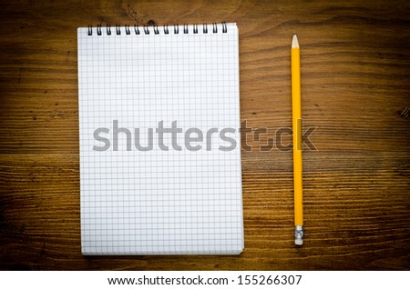Black notebook with pencile on a wood background