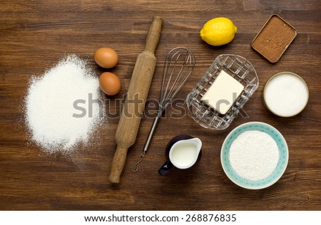 Rural vintage wooden kitchen table with baking cake ingredients (chocolate, eggs, flour, milk, butter, sugar). Background layout with free recipe text space.