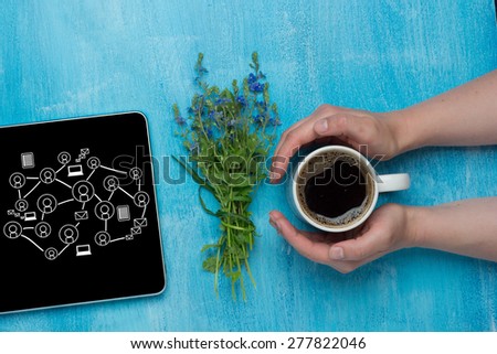 Woman holding hot cup of coffee and tablet computer with flowers. Social network concept.