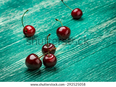 Cherries on wooden table with water drops macro background.