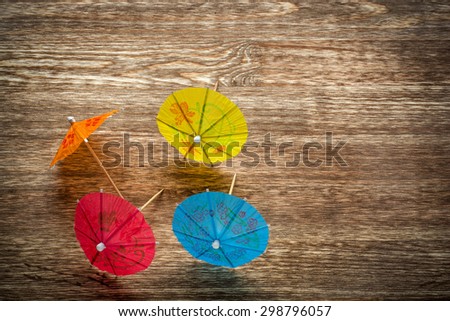 Colourful cocktail umbrellas lying on a wooden backdround, conceptual for partying and festivity.