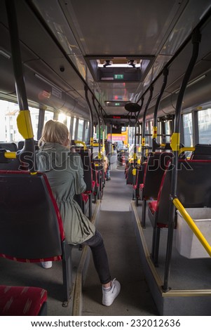 Teenage girl riding the bus, sitting at the back facing forward