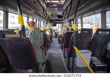Teenage girl riding the bus, sitting at the back facing forward