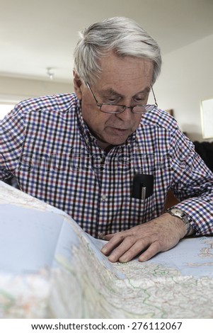 An older genteleman reading a map at home