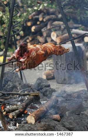 Lamb being roasted whole on a spit over open fire in medieval settings