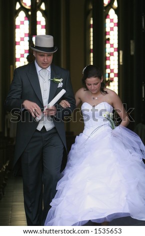 A wedding, bride and groom walking hand in hand out of church after ceremony