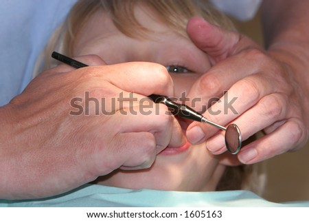 A young boy at the dentists, dentist taking a look into his mouth using various tools