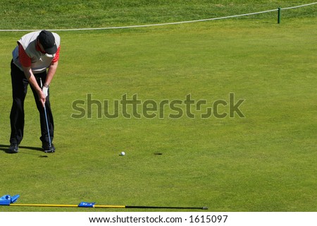 Golfer putting the ball into the hole in a tournament, ball heading towards hole