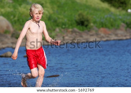 A young boy running in a lake, cooling off on a hot summerday