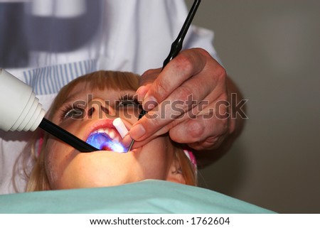 A young girl at the dentists, dentist taking a look into her mouth using various tools