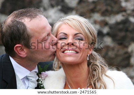 A very happy couple sitting together and smiling, very much in love, man kissing wife