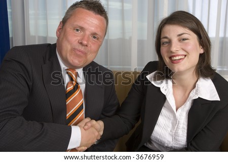 A businessman an businesswoman smartly dressed, shaking hands after making a deal
