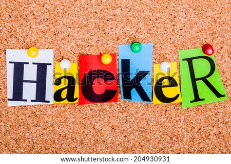 The word Hacker in cut out magazine letters pinned to a cork notice board