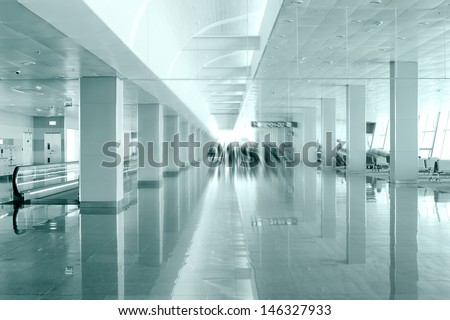 Travel concept. Passengers in the modern airport terminal waiting room going to flight departure area. Image in blue colors with blur