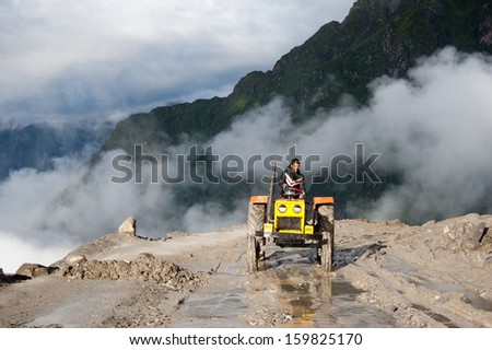 ROHTANG PASS, INDIA - SEPTEMBER 05: Unidentified Indian man driving tractor, working at road construction on Rohtang pass at Manali - Leh  highway. India, Himachal Pradesh, September 05, 2012