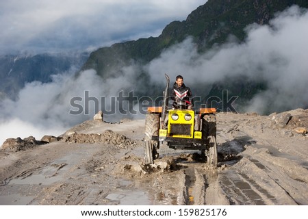 ROHTANG PASS, INDIA - SEPTEMBER 05: Unidentified Indian man driving tractor, working at road construction on Rohtang pass at Manali - Leh  highway. India, Himachal Pradesh, September 05, 2012
