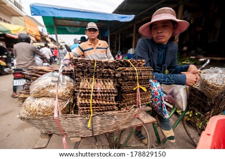 SIEM REAP, CAMBODIA - DEC 22, 2013: Unidentified Khmer people selling smoked fish at traditional marketplace on Dec 22, 2013 in Siem Reap, Cambodia. Street food markets is popular tradition in asia